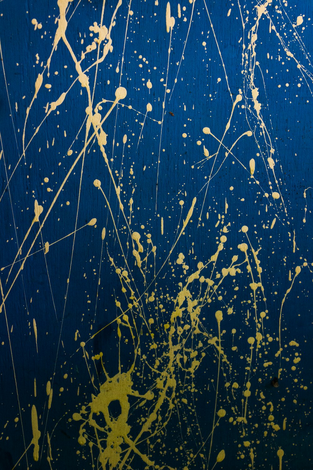a blue wall with yellow paint splattered on it