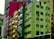 A series of colorful, multi-story apartment buildings with vibrant facades, featuring colors such as green, yellow, orange, and magenta. Each building has numerous windows, some with air conditioning units. The structures appear to be densely packed in an urban setting.