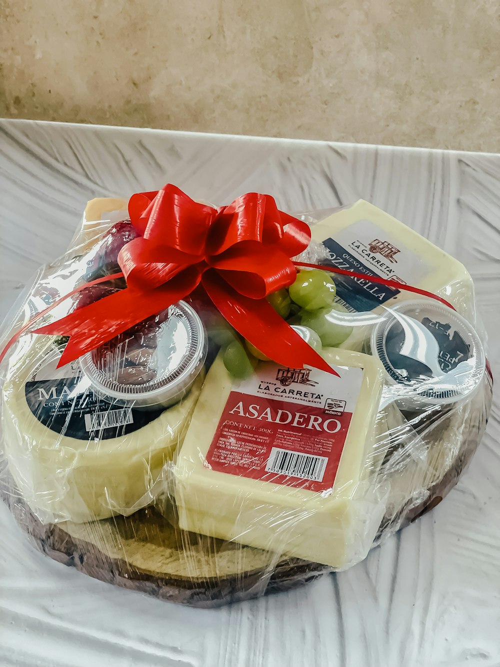 a basket of cheese with a red bow on top of it