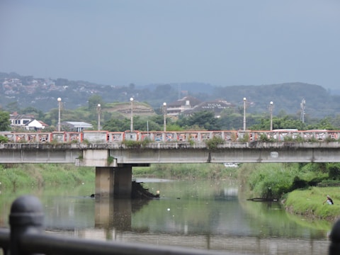 A wide shot of a modern concrete bridge spanning a river with green surroundings.