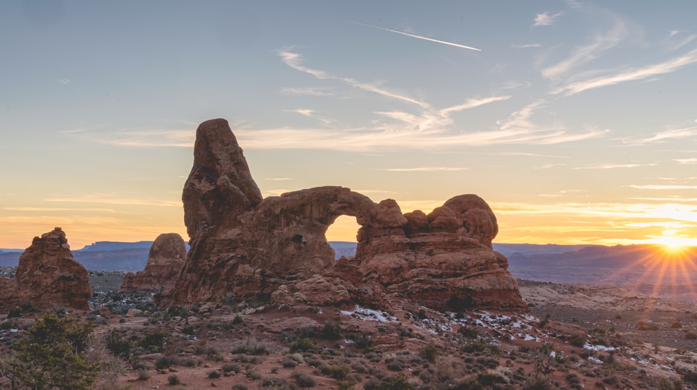 the sun is setting over the rocks in the desert