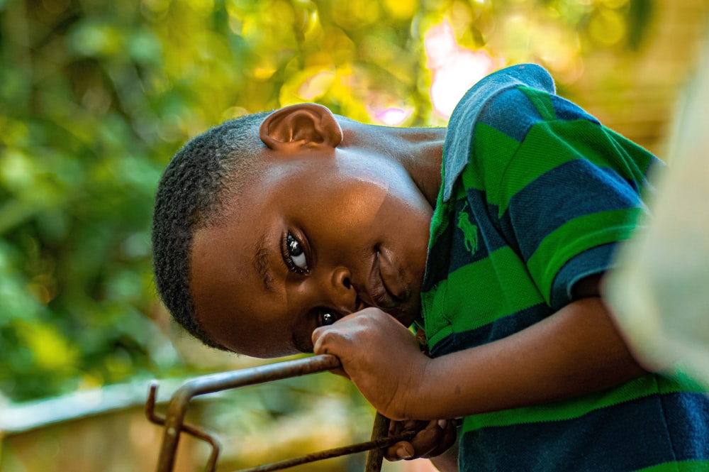 a young boy leaning on a metal rail