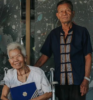 A Vitalis agent assisting a senior couple with paperwork in a cozy, welcoming environment.