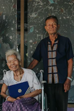 Senior couple happily checking into a hotel with friendly staff assistance.
