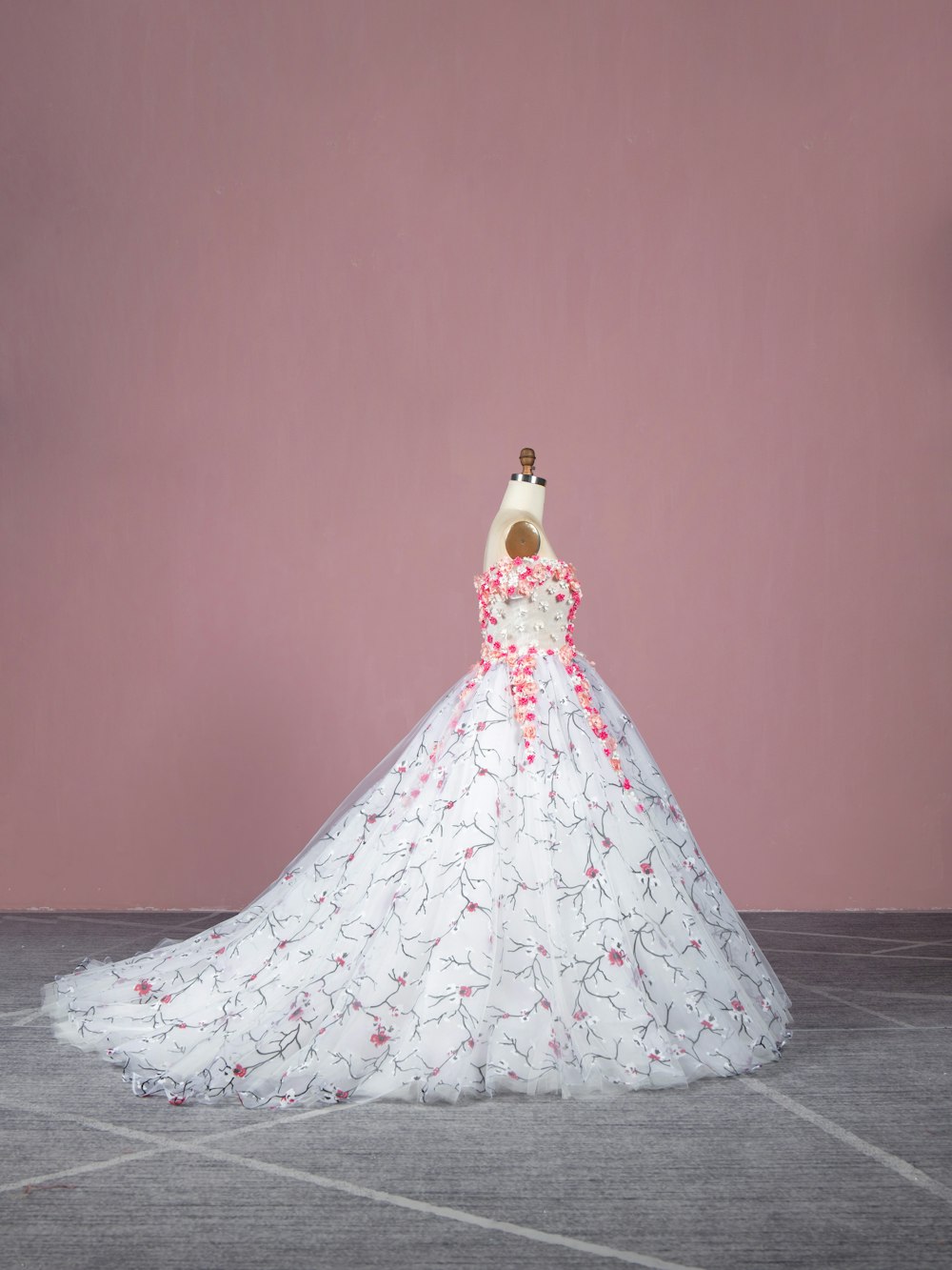 a white wedding dress with pink flowers on a mannequin