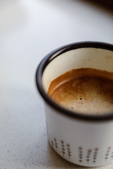 A ceramic coffee mug featuring a creative design, placed next to a steaming cup of coffee.
