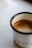 A stylish mug with a unique design placed next to a steaming cup of coffee.