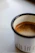 A close-up of a vibrant, hand-thrown ceramic mug filled with steaming coffee, resting on a cozy wooden table.