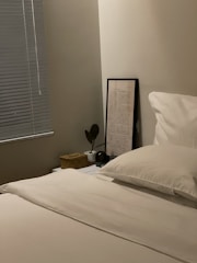 Neat bed with clean white linens and a small bedside table in a quiet room.