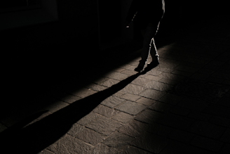 A shadowy silhouette of a lone figure walking along a cobblestone street at dusk, evoking past lives.