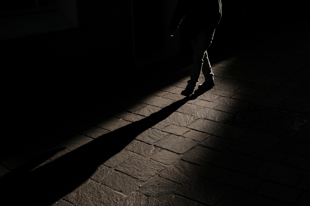 a person standing in the dark with their shadow on the ground