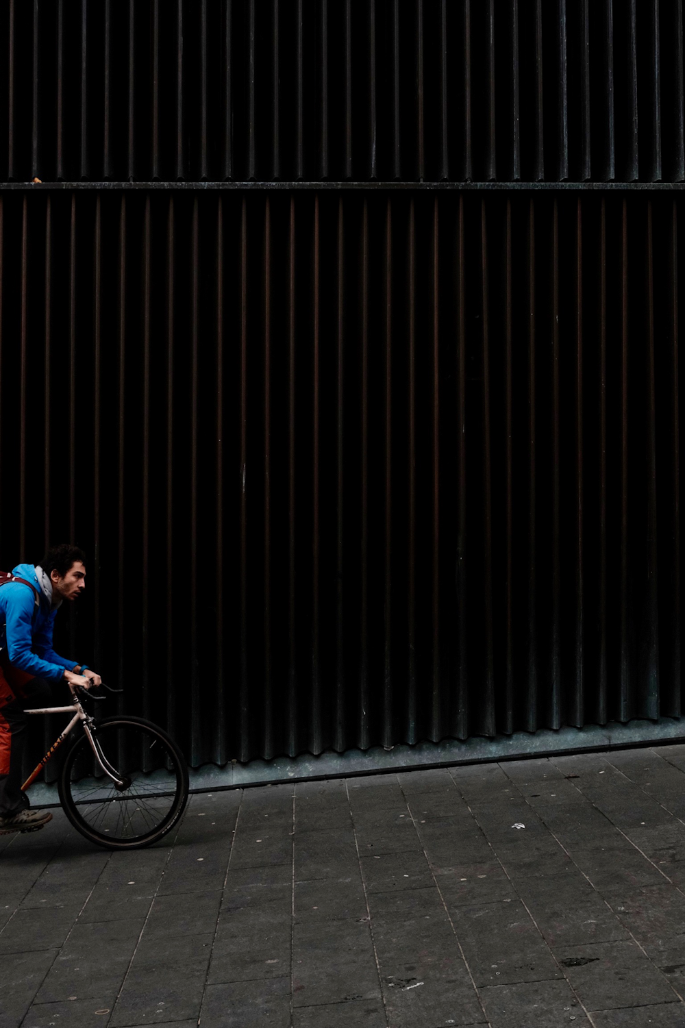 a man riding a bike down a street next to a tall building