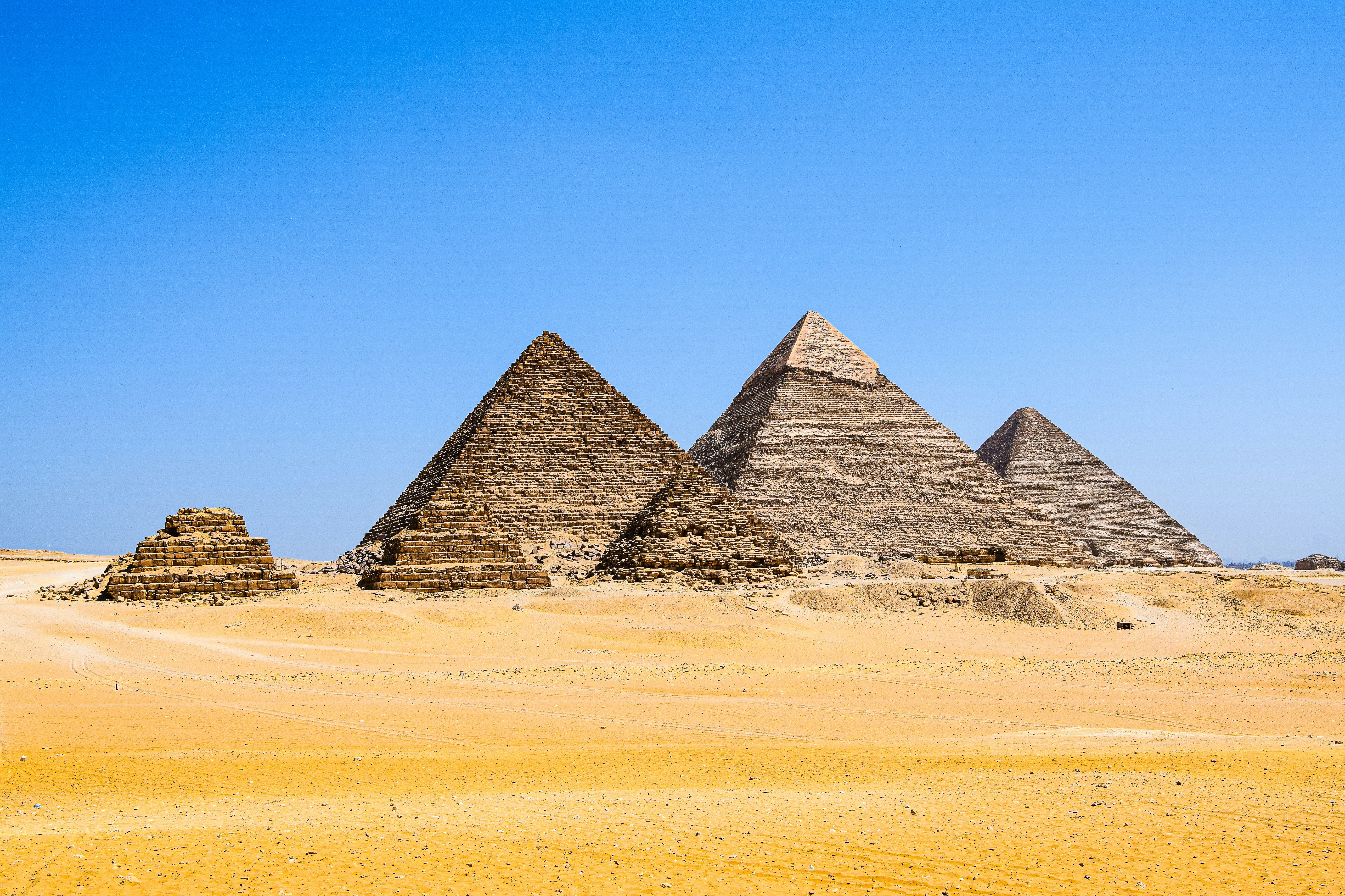 Three pyramids in the desert with a blue sky in the background photo ...