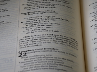 A close-up view of text from an open book, focusing on verses and prophecies from a religious script. The page numbers and chapters are visible, with some parts of the text emphasized in bold.