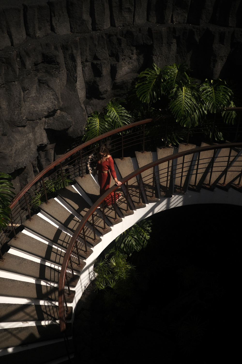 a woman is walking down a spiral staircase
