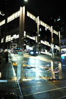 Nighttime exterior render with illuminated windows and reflective surfaces.