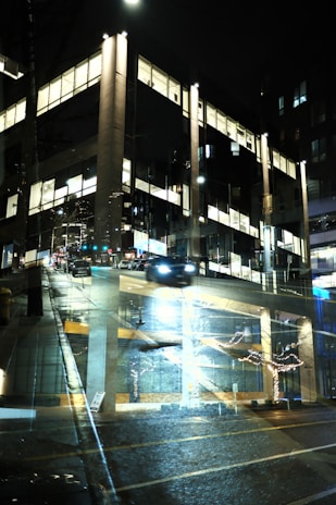 Nighttime visualization of a commercial building with illuminated windows and street activity.