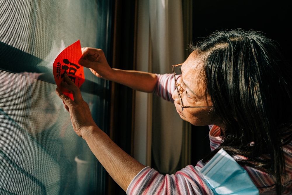 a woman holding a piece of paper in front of a window