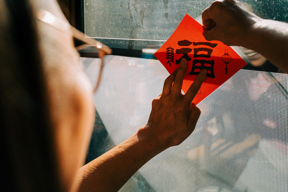 a person holding a red kite with a chinese writing on it