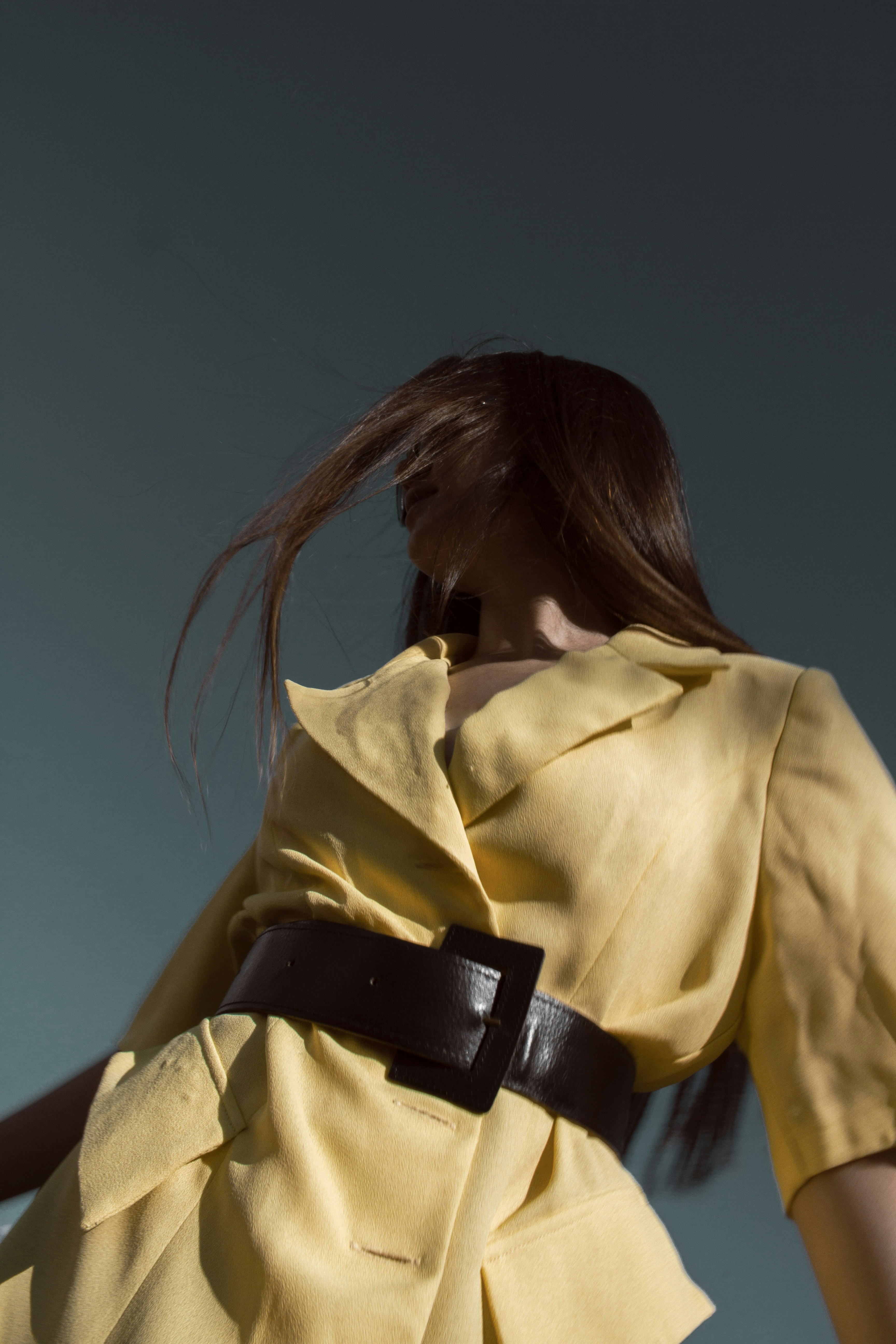 une femme en robe jaune avec ceinture noire