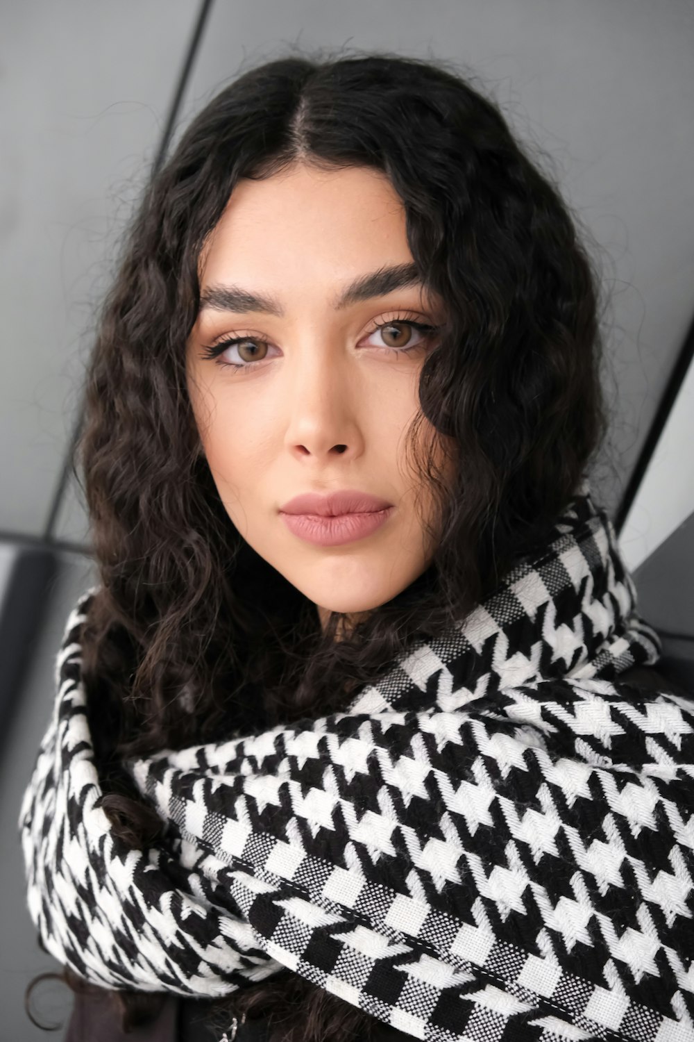 a woman with curly hair wearing a black and white scarf