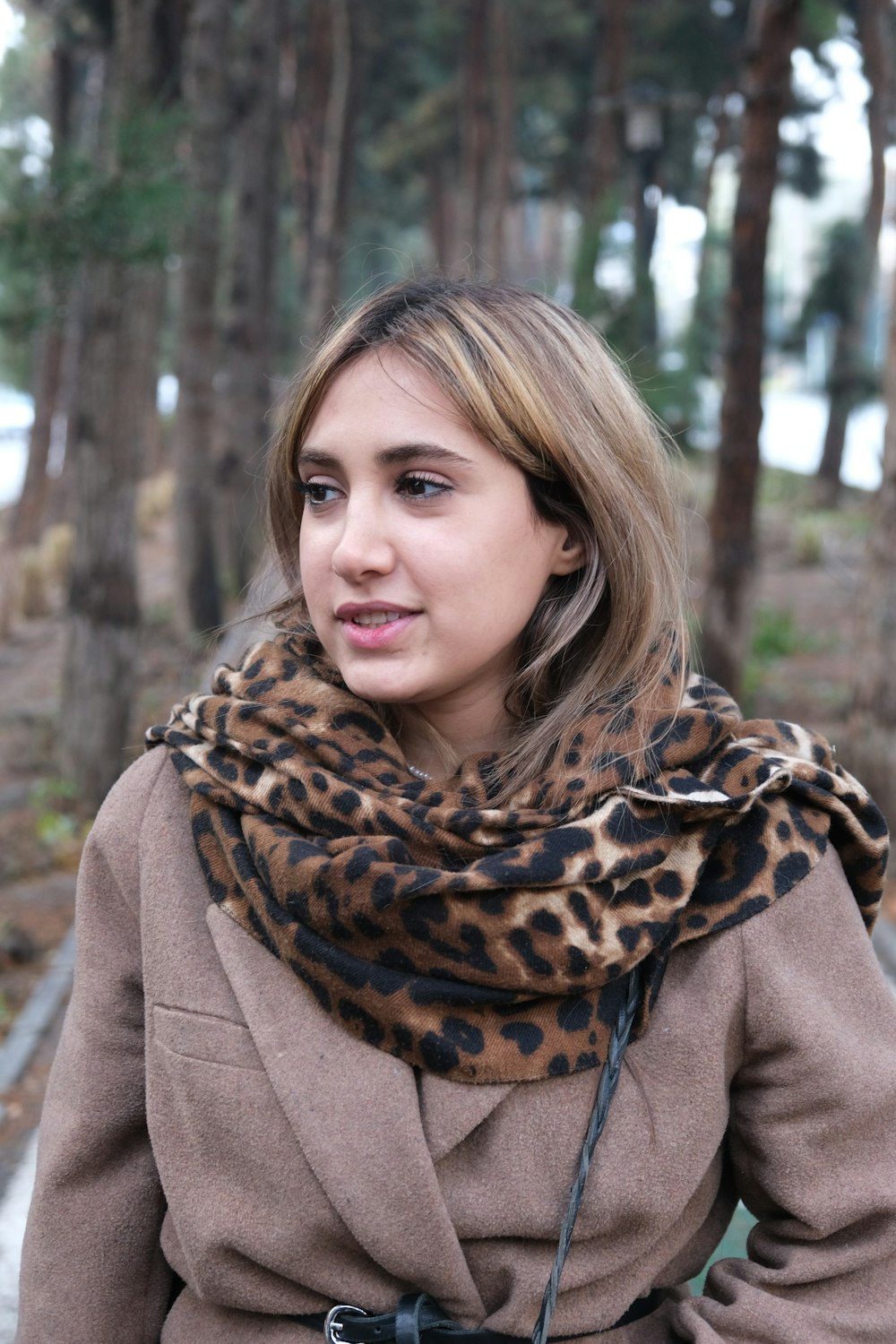 a woman wearing a coat and a leopard print scarf