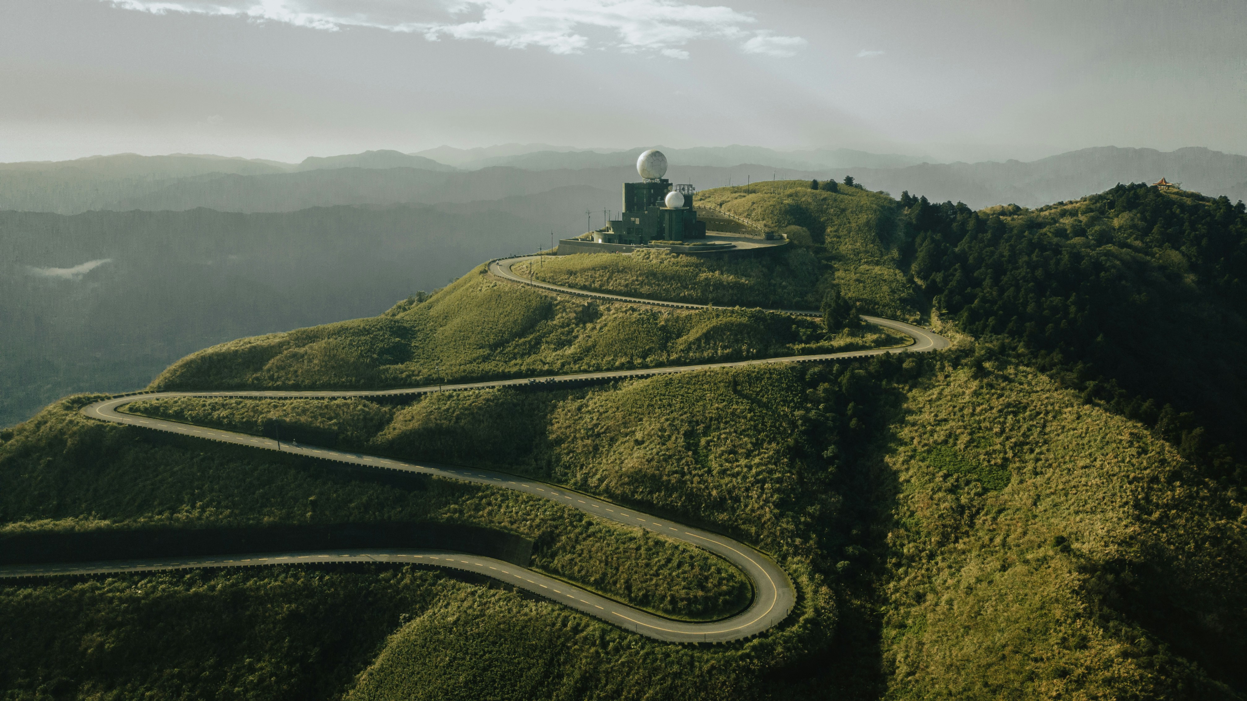 a winding road on top of a green mountain