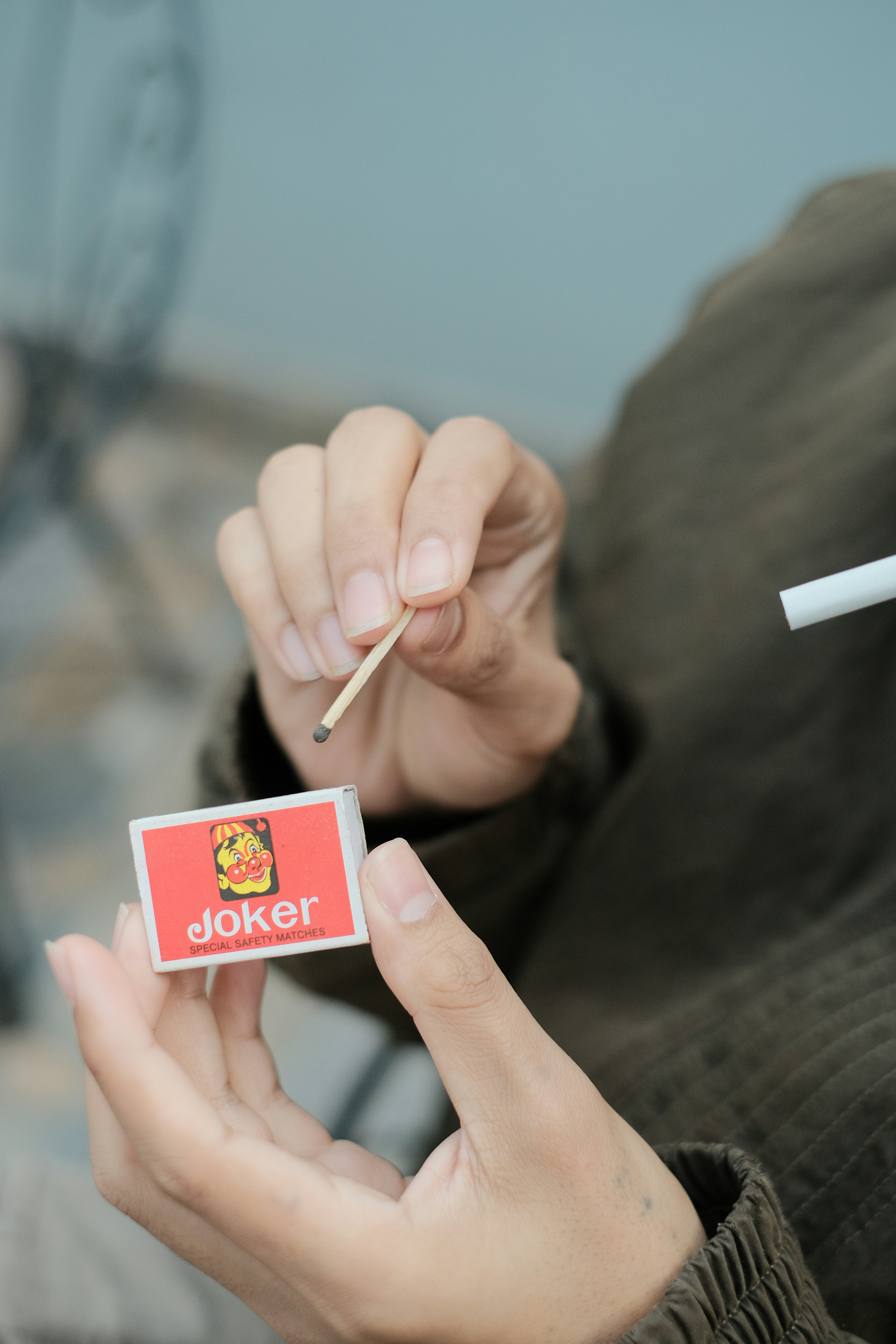 a person holding a cigarette and a cigarette stick