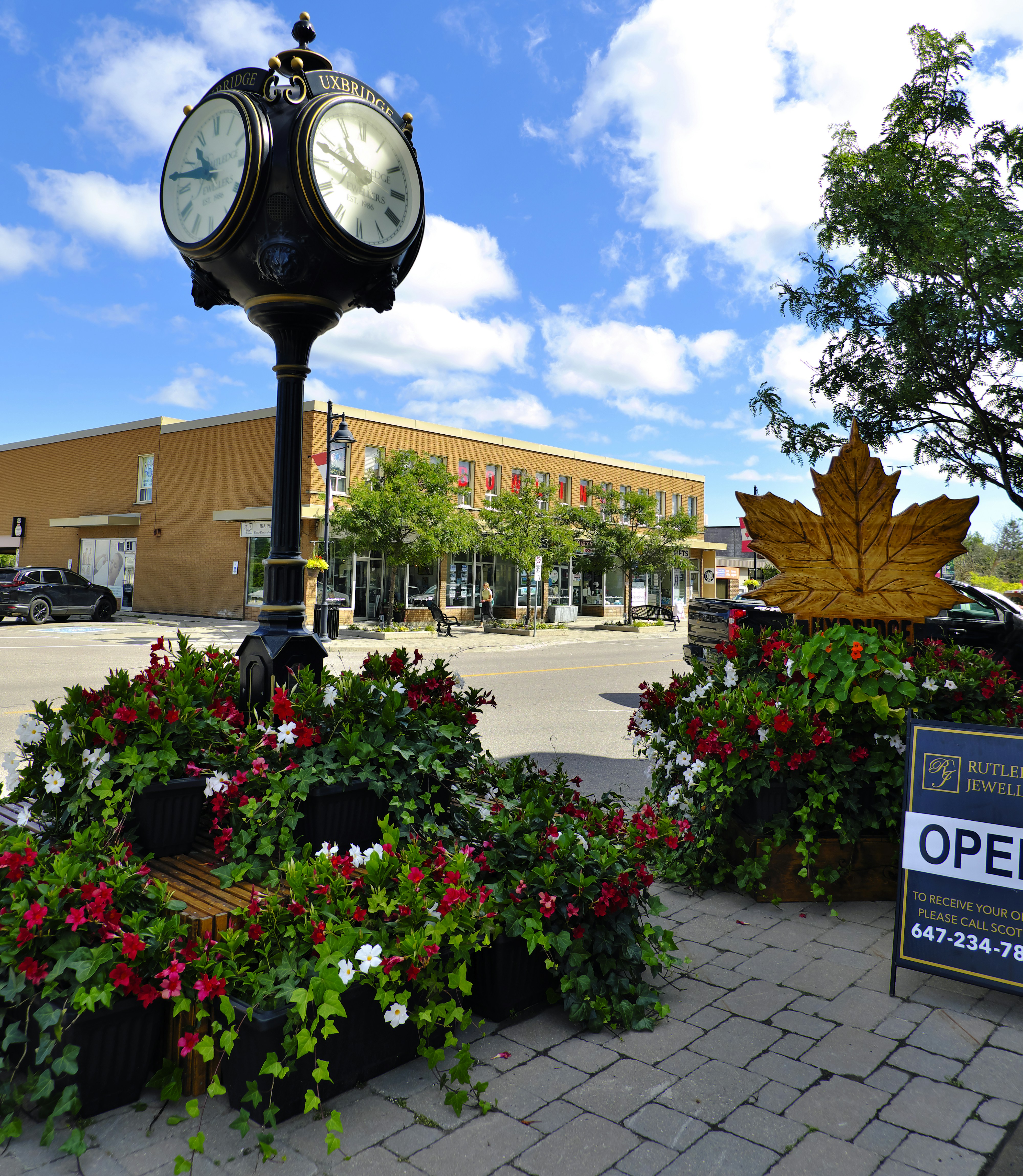 a clock on top of a pole surrounded by flowers