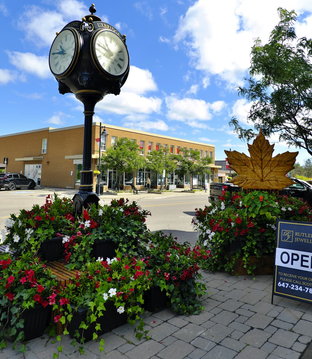 a clock on top of a pole surrounded by flowers