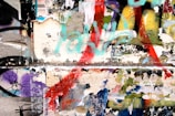 A colorful collage of peeling posters and graffiti on a wall, featuring layers of torn paper and various spray-painted shapes and colors. The artwork blends together, creating a chaotic yet visually engaging scene.