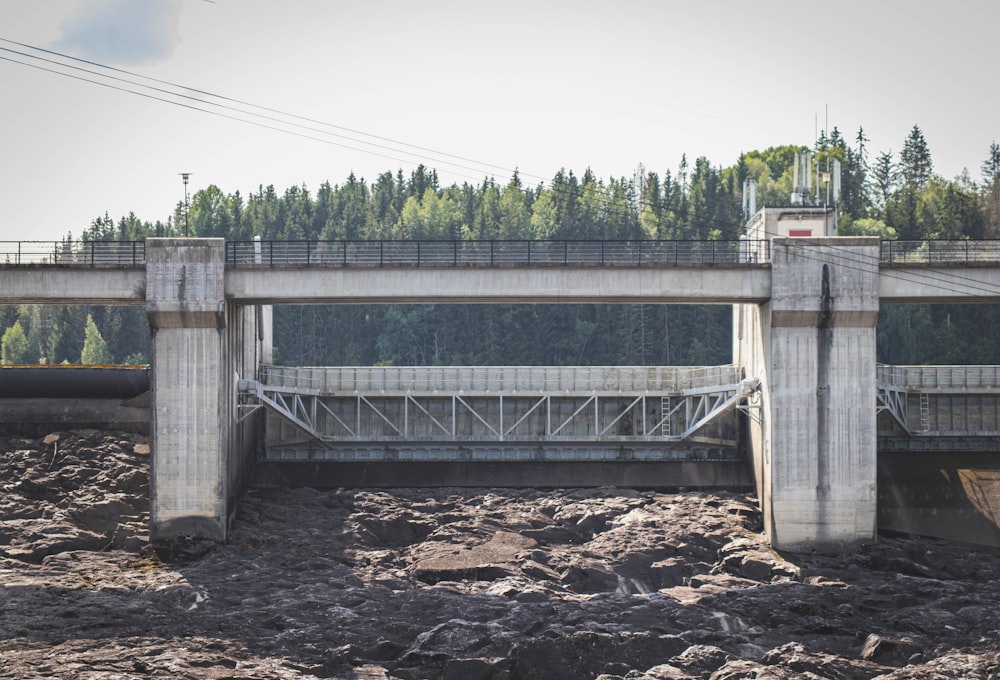 a bridge over a muddy river with trees in the background