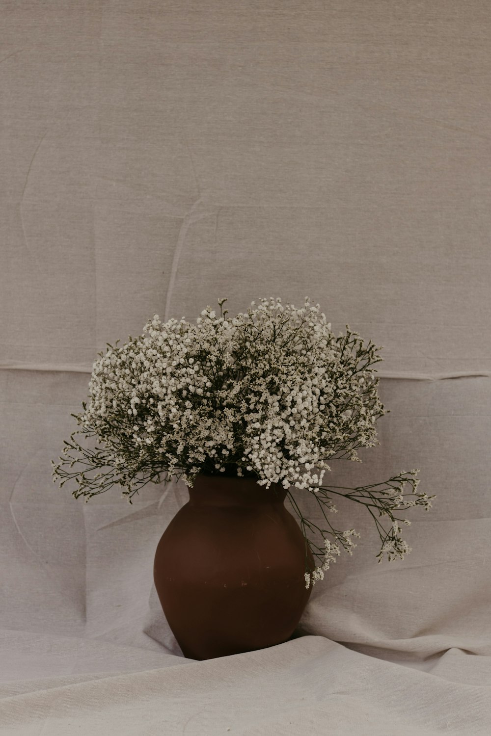 a brown vase filled with lots of white flowers