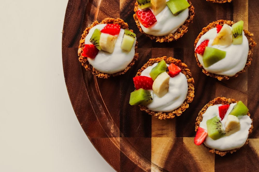 a wooden plate topped with mini desserts covered in fruit