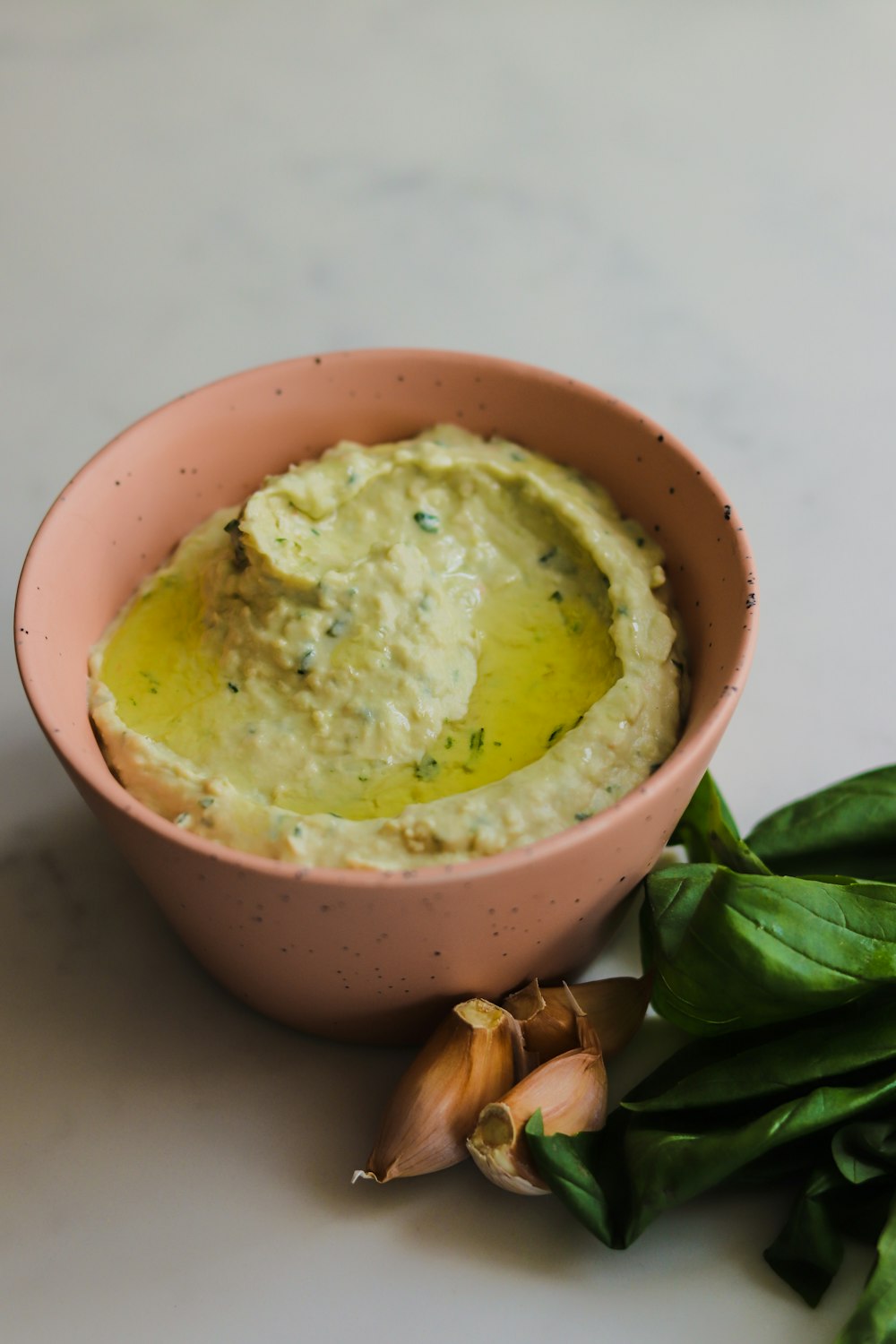 a bowl of hummus next to some garlic