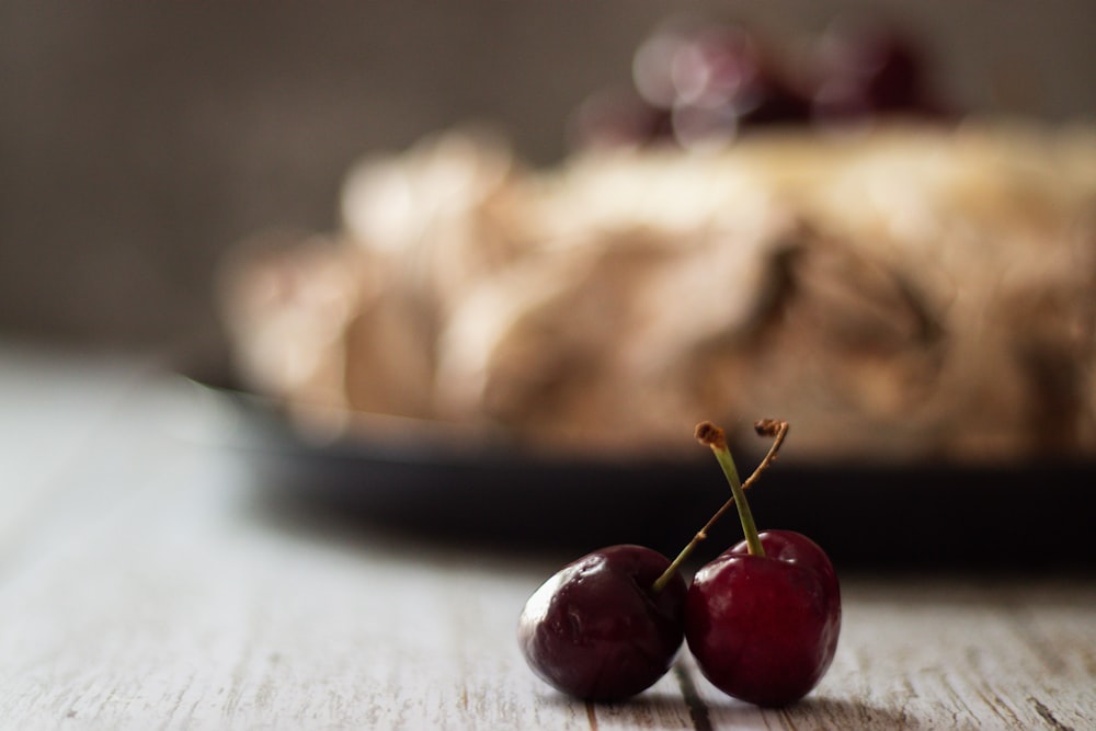 two cherries sitting on a table next to a pie