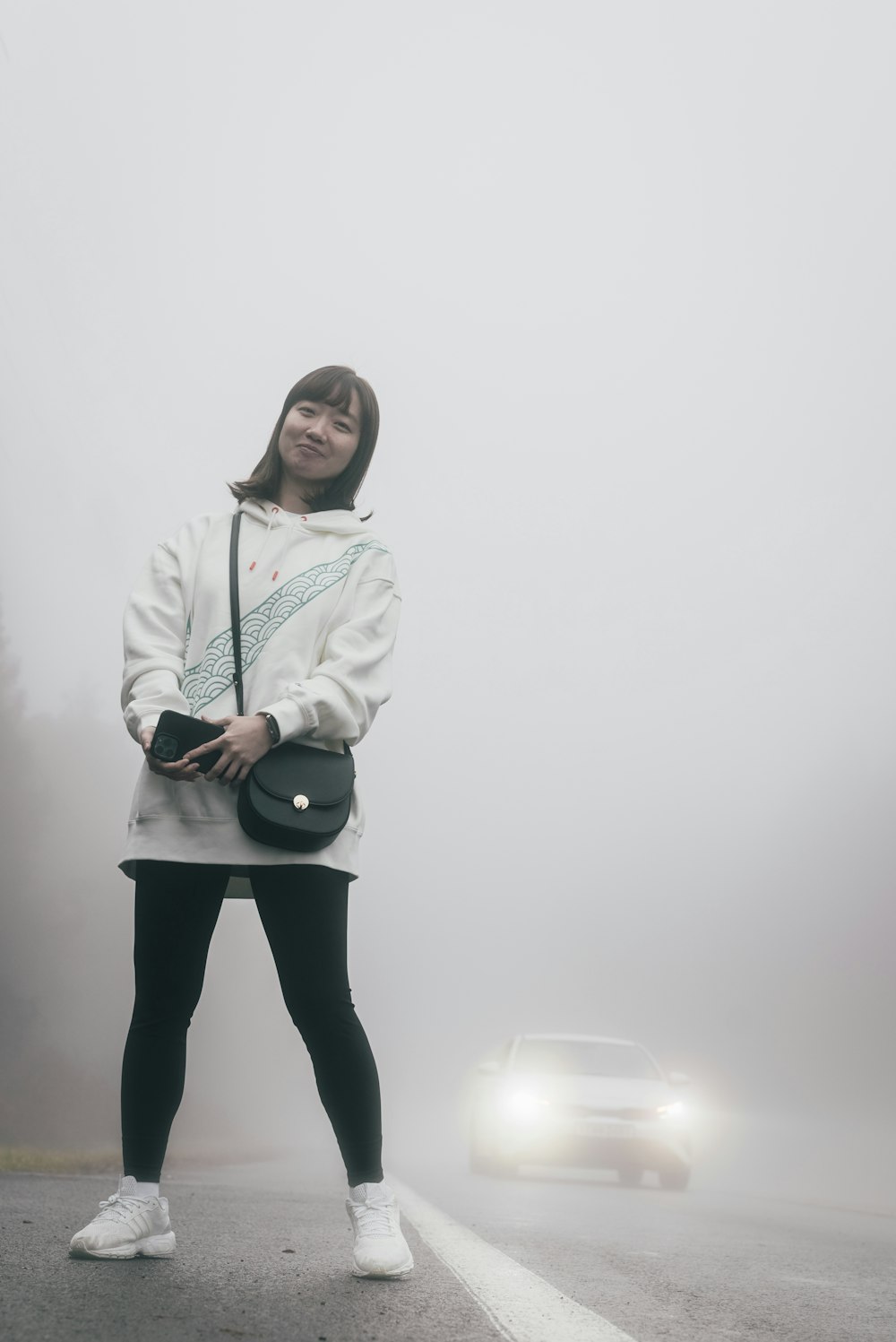 a woman standing in the middle of a foggy road