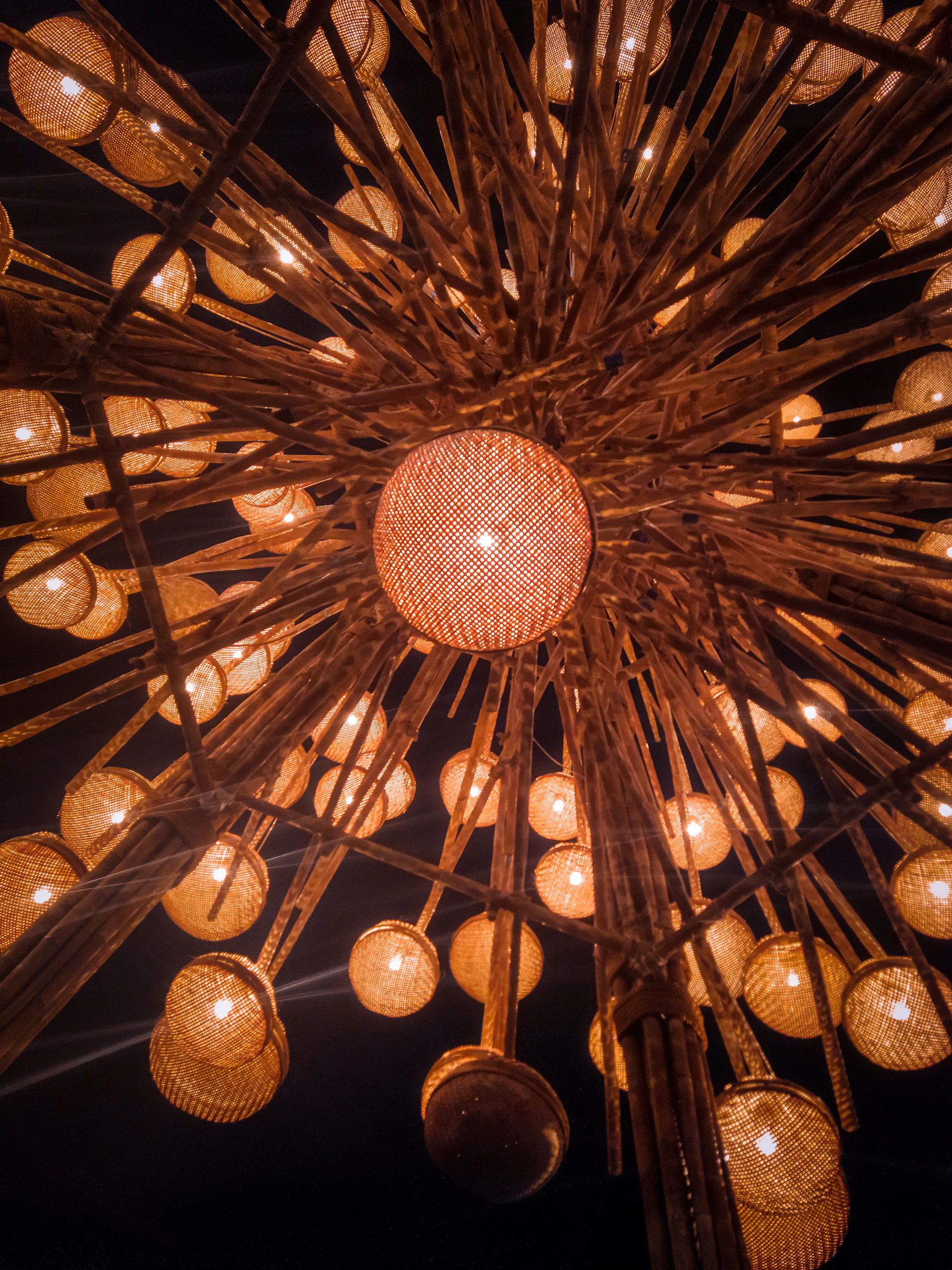 Close-up of delicate, glowing lanterns hanging from rustic beams, casting gentle light and shadows.