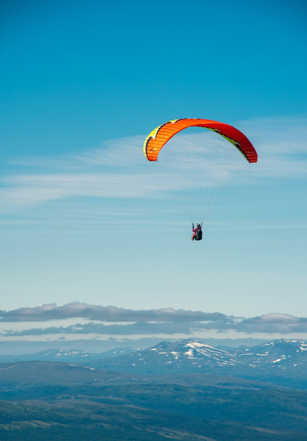 a person parasailing in the sky with mountains in the background