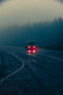Our tow truck navigating a rainy highway, headlights cutting through the mist