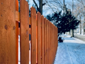 a close up of a wooden fence in the snow