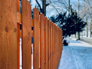 a close up of a wooden fence in the snow