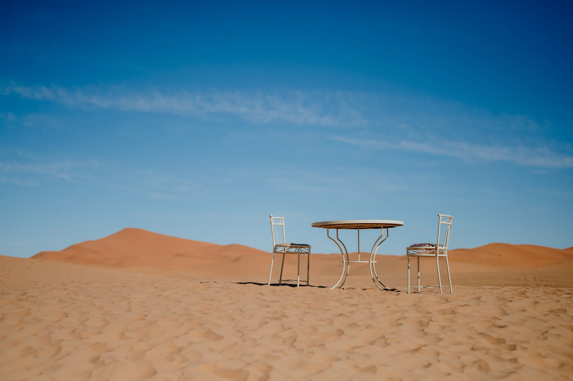 A camp table and two chairs set out alone on a desert dune