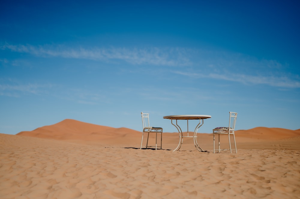 two chairs and a table in the middle of a desert