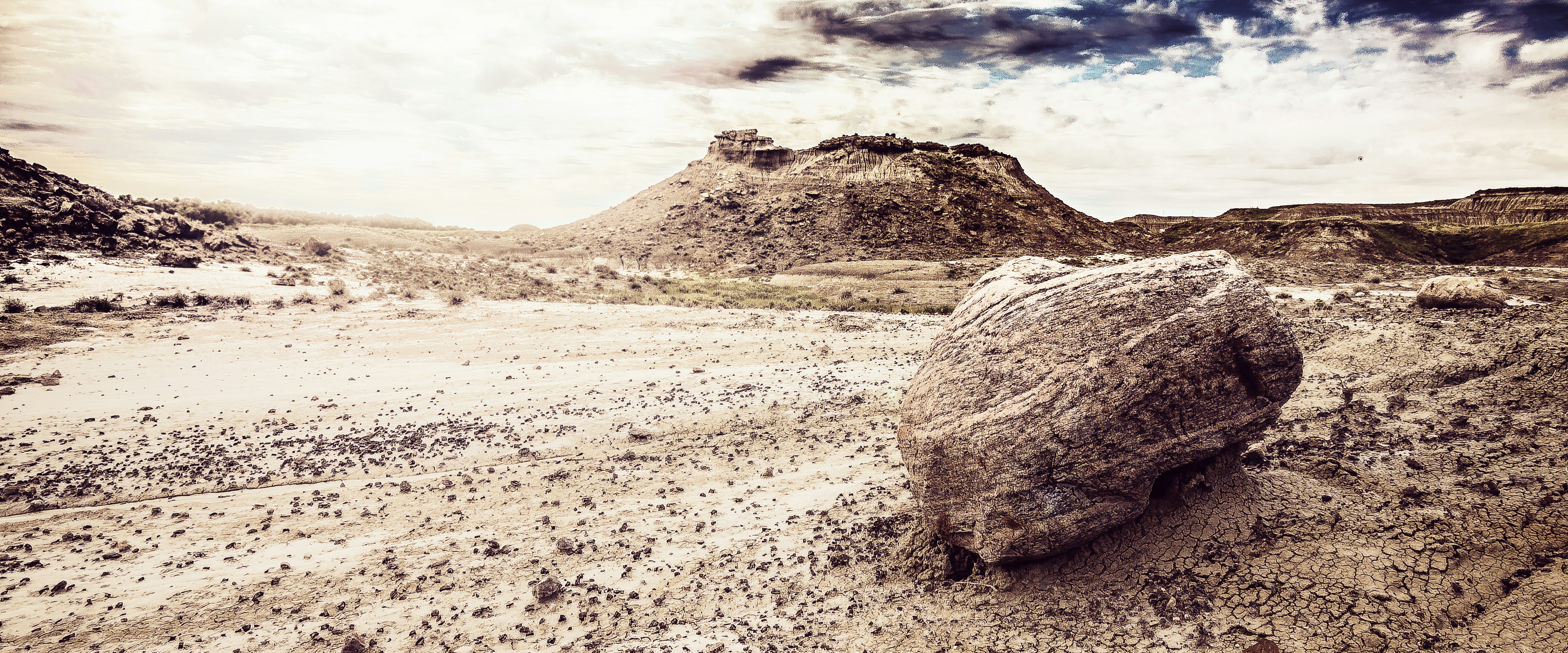 a large rock sitting in the middle of a desert