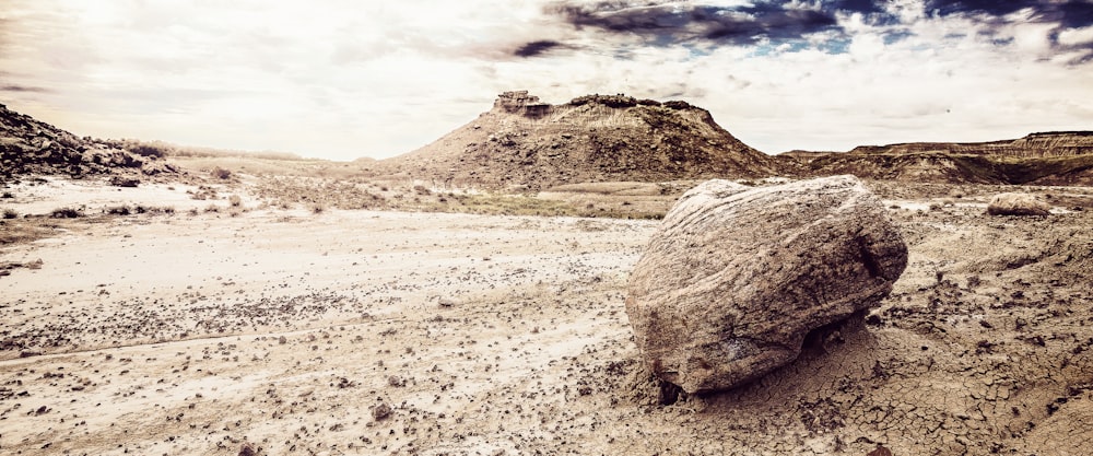 a large rock sitting in the middle of a desert