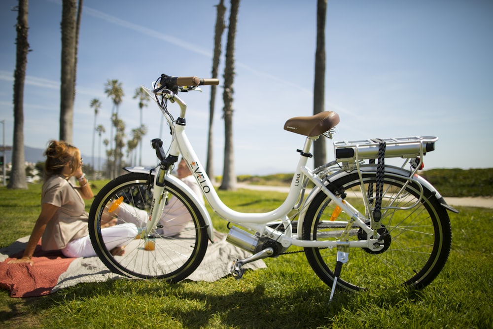 a woman sitting on the grass next to a bike