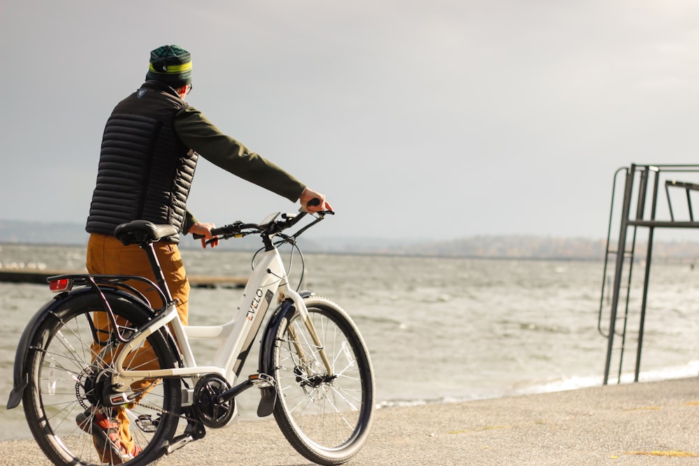 a man riding a bike next to the ocean