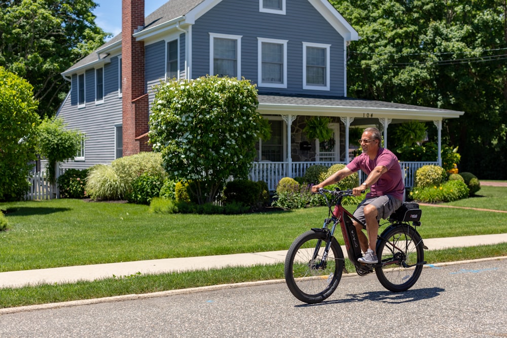 a man riding a bike down a street next to a house