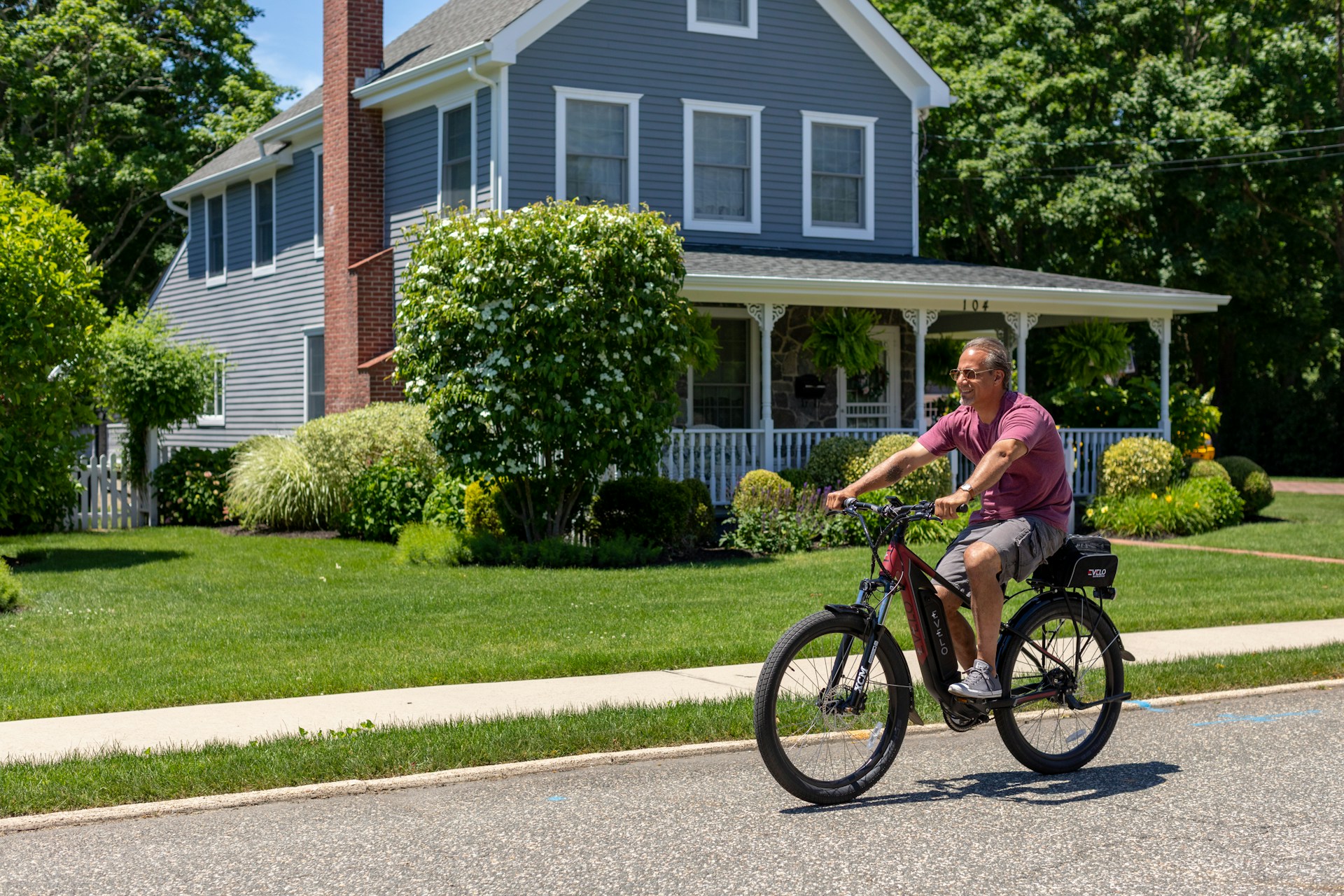 A cheerful older adult riding a sleek electric tricycle along a sunny park path, showcasing comfort and ease.